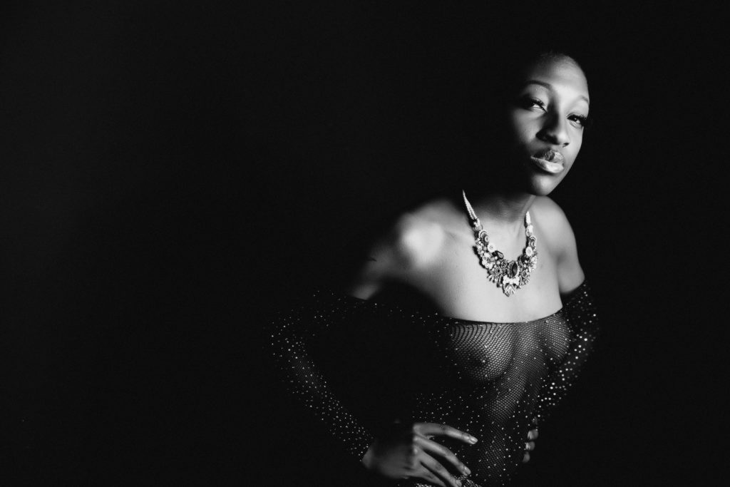 boudoir image with woman in black bodysuit and black background; women's empowerment photography by Lindsay Hite
