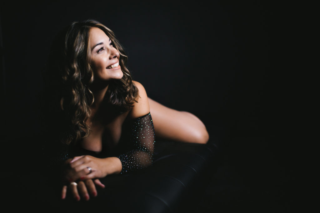 Woman in sparkly fishnet body suit in black background, boudoir photography by Lindsay HIte