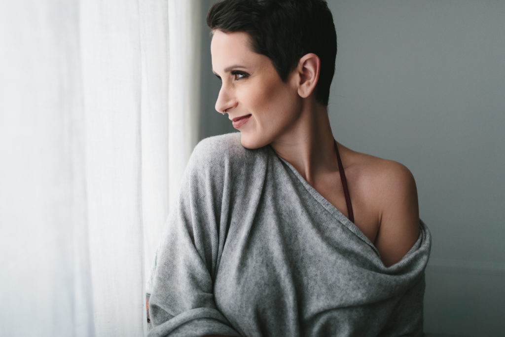 Woman in oversized sweater looking out the window, beauty by Michelle DeVoe, photography by Lindsay Hite