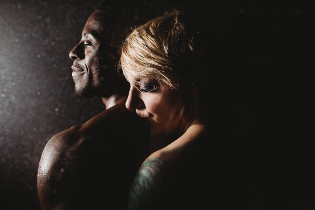 Couple standing close with a black backdrop. Photography by Lindsay Hite.