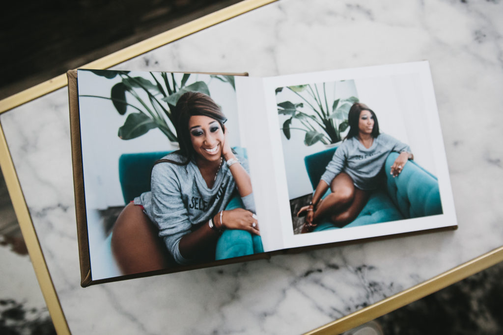 Open album sitting on a marble table displaying two portraits of an African American woman. Photography by Lindsay Hite of Show Your Spark