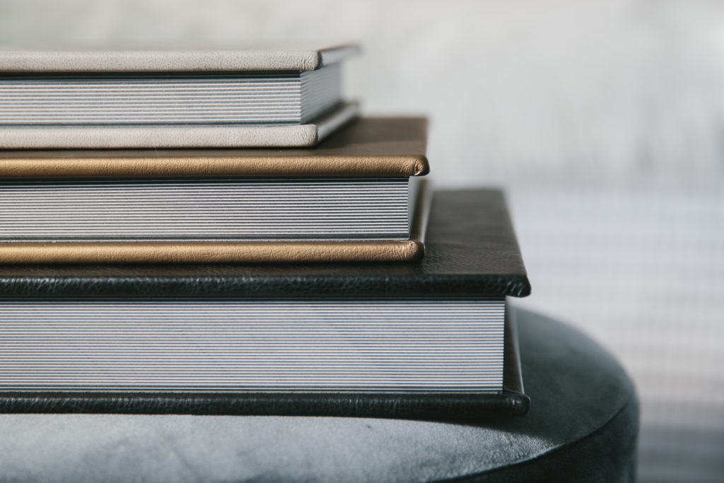 Side image of 3 different sized leather albums, displaying the thickness of the albums. 