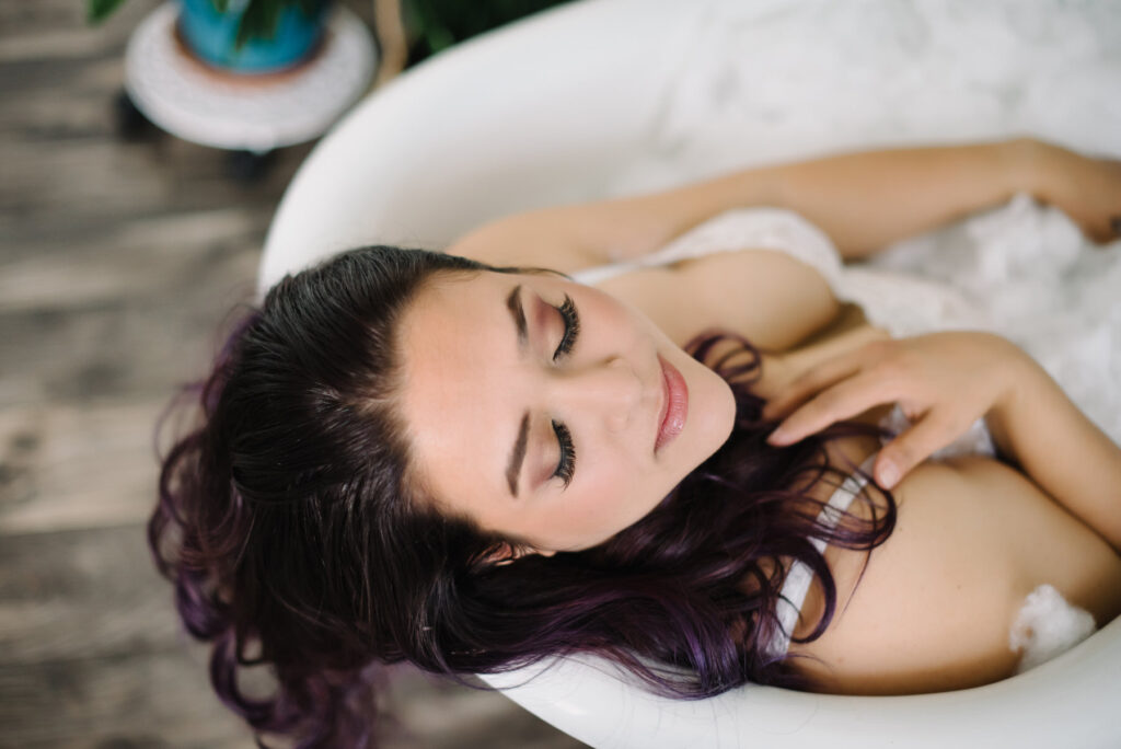 Brunette with long hair in white lingerie in white bathtub; Boudoir Photography by Lindsay Hite