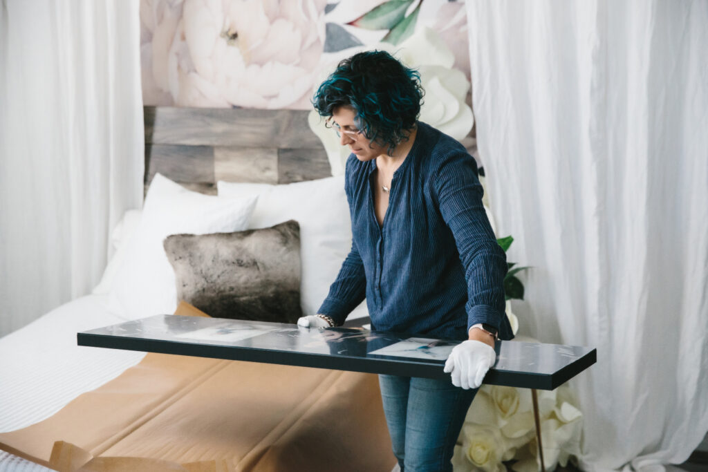 Image of woman holding and inspecting large piece of wall art