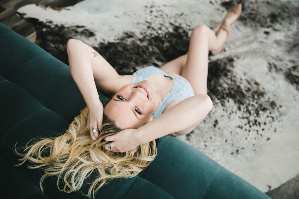 Woman in ice blue bra leaning back against a teal sofa. Boudoir photography by Lindsay Hite