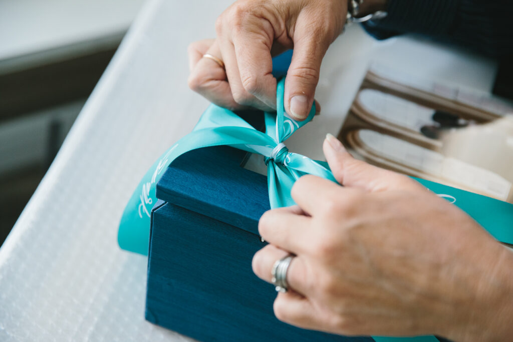 Woman tying a bow on a piece of artwork; photography by Lindsay Hite