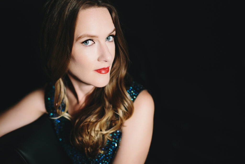 Embrace Your Fierceness through photography, woman in green sparkly dress sitting on a couch with a dark background.  Photography by Lindsay Hite