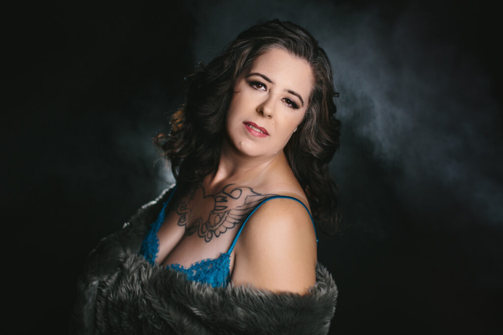 Woman in teal lingerie and fur wrap with a dark backdrop. Photography by Lindsay Hite