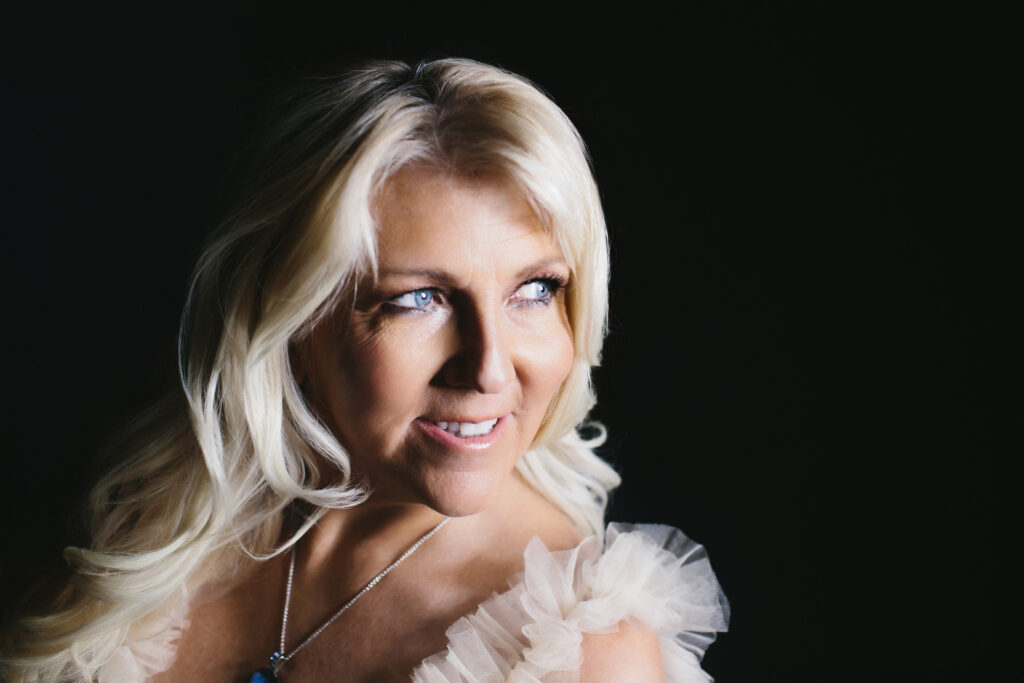Woman in off-white gown with a black backdrop.  Photography by Lindsay Hite