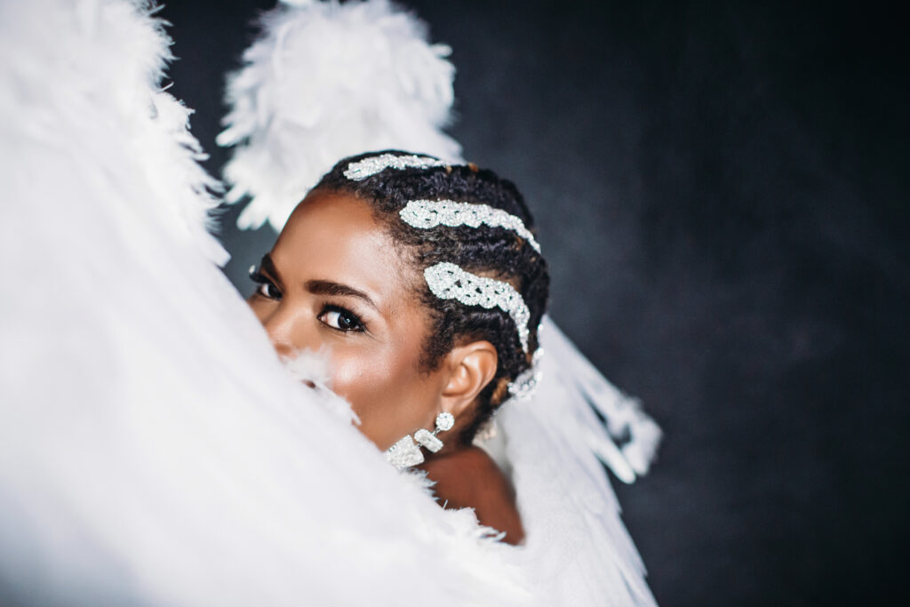 Woman over forty wearing giant white wings with white background. Photography by Lindsay Hite