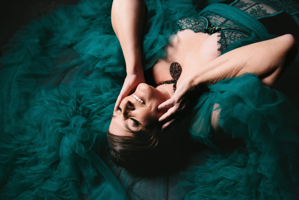 Woman in teal lingerie and robe laying on her back. Photography by Lindsay Hite