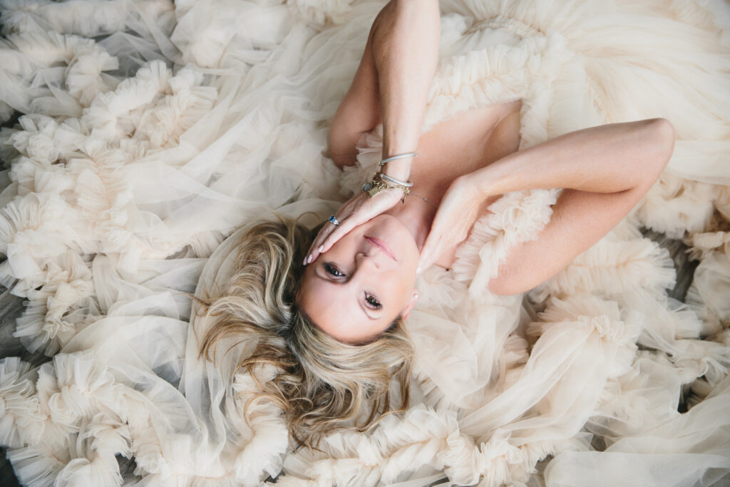 A woman in a blue toile dress lying on the ground.  Photography by Lindsay Hite. 