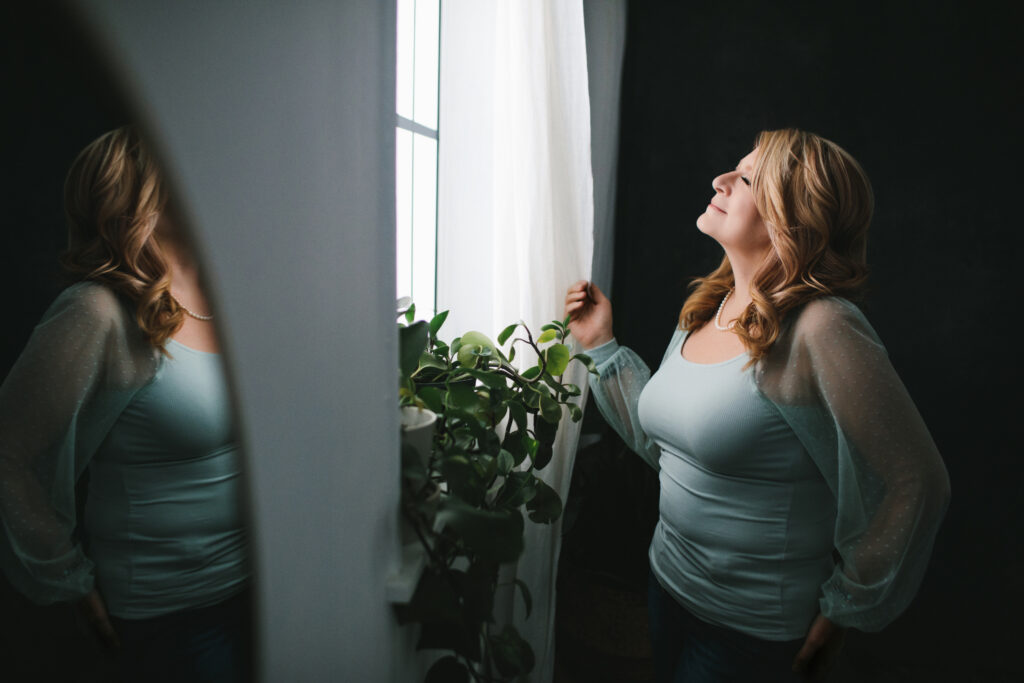 Woman looking out the window knowing her worth. Photography by Lindsay Hite