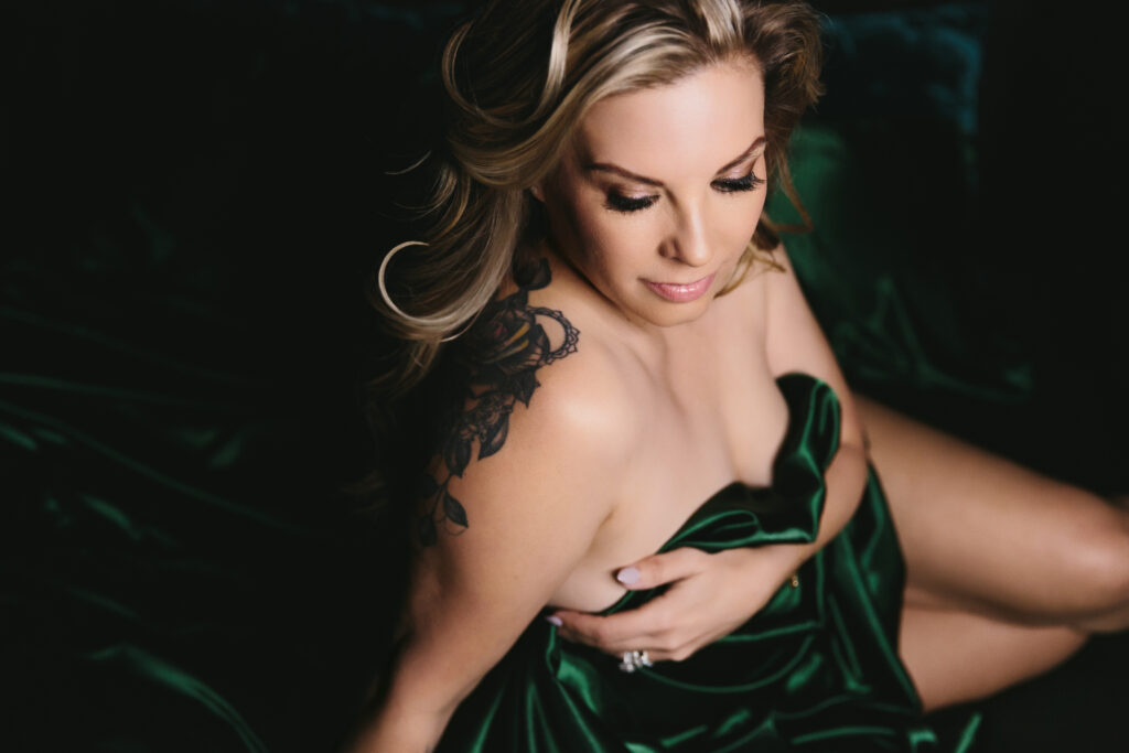 Woman between emerald green sheets. Photography by Lindsay Hite