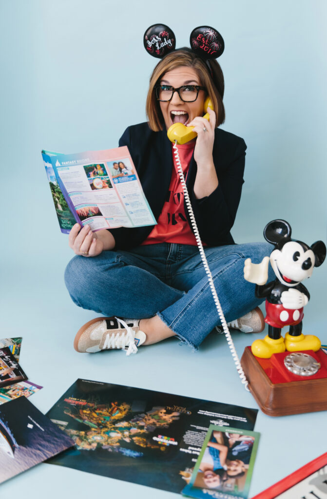 Woman wearing Mickey Mouse Ears, with Disney items surrounding her. Photography by Lindsay Hite