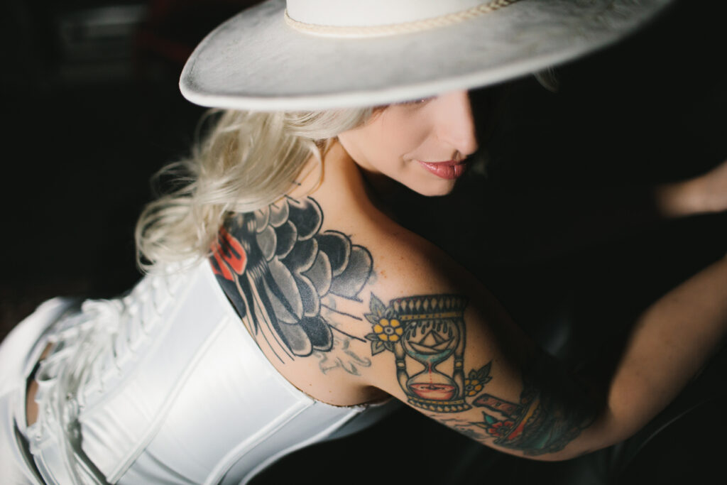 Woman in a white corset and white hat against a black background