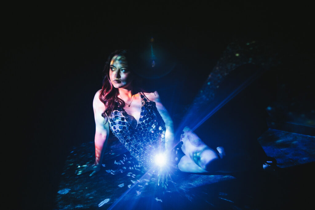 Woman in a sequin dress with the lights reflecting off her.