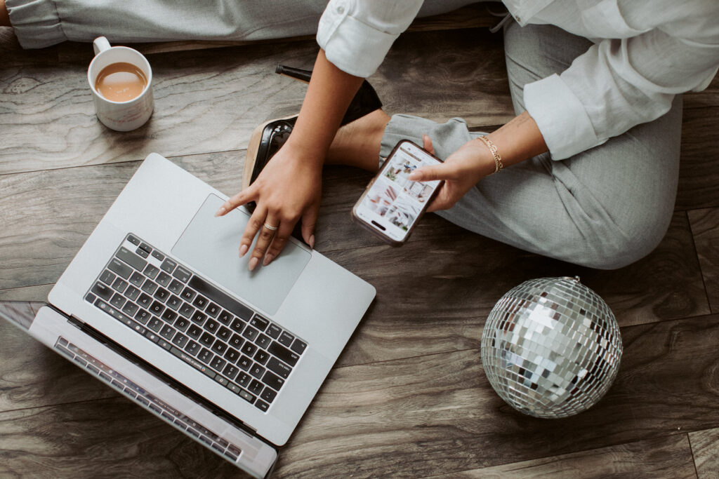 Flat lay branding image of a woman sitting on the ground using her laptop and phone. Photography by Lindsay Hite