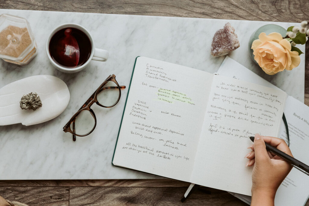 Flat lay of a woman writing in her journal with crystals on the table. Photography by Lindsay Hite