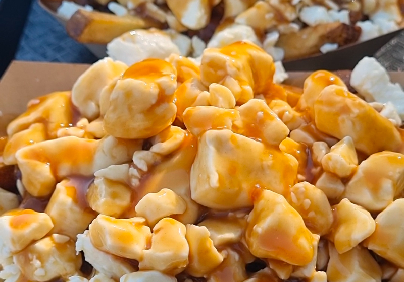 Assiette de poutine avec des frites, du fromage en grains et une sauce brune riche.