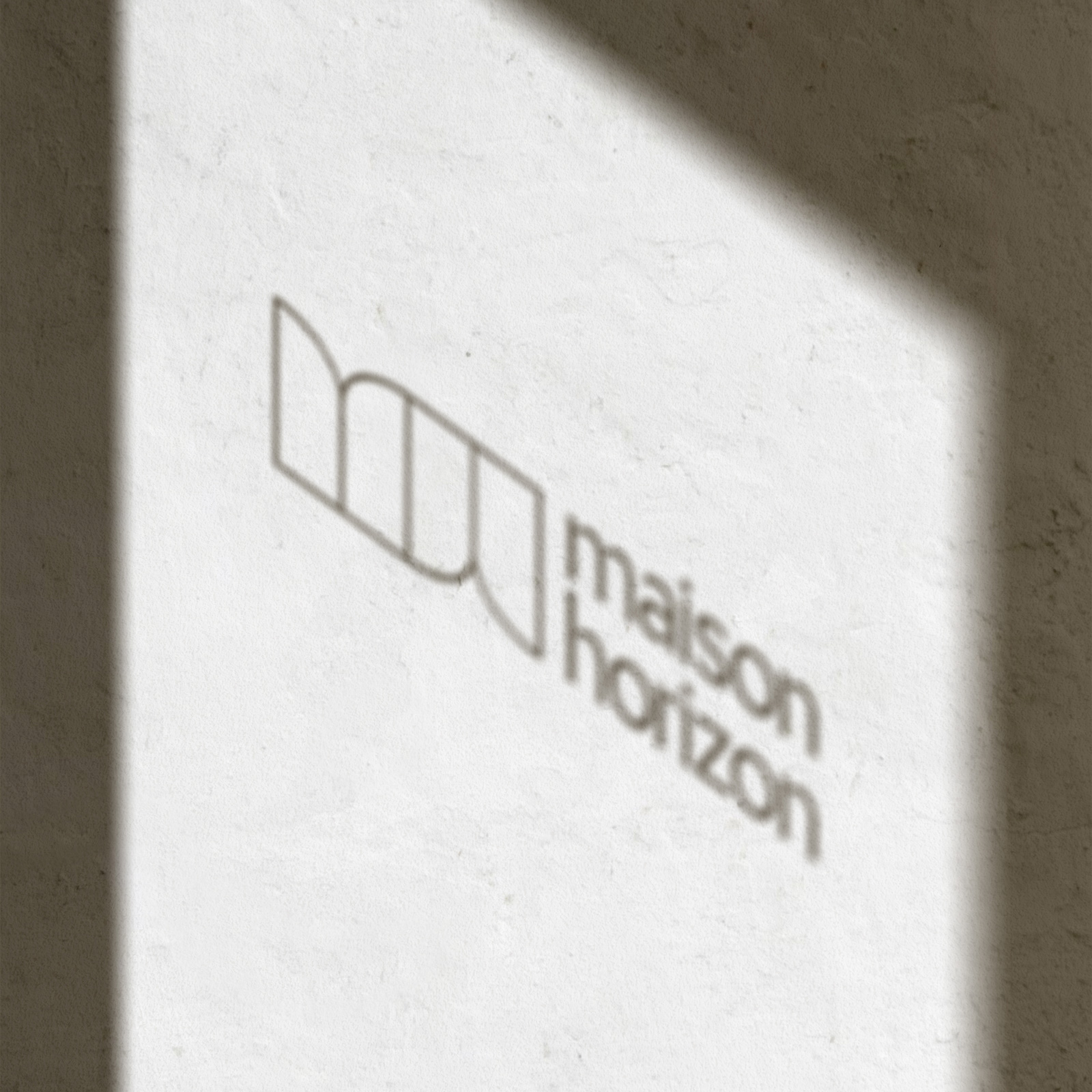 Ombre du logo Maison Horizon sur un mur en pierre