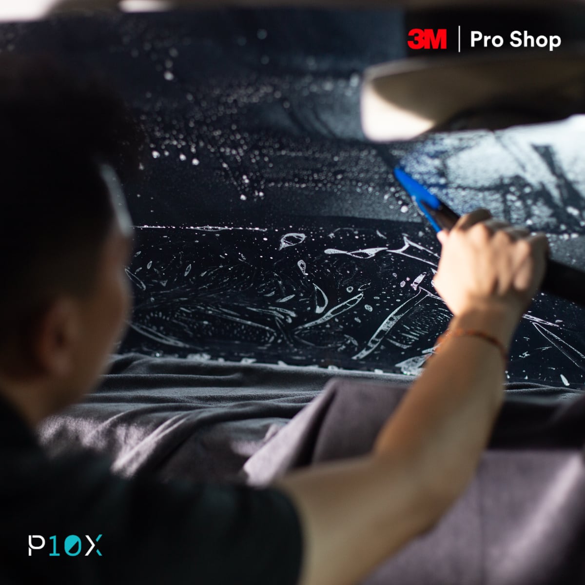 Car window tint installation showing professional squeegee technique for bubble-free application