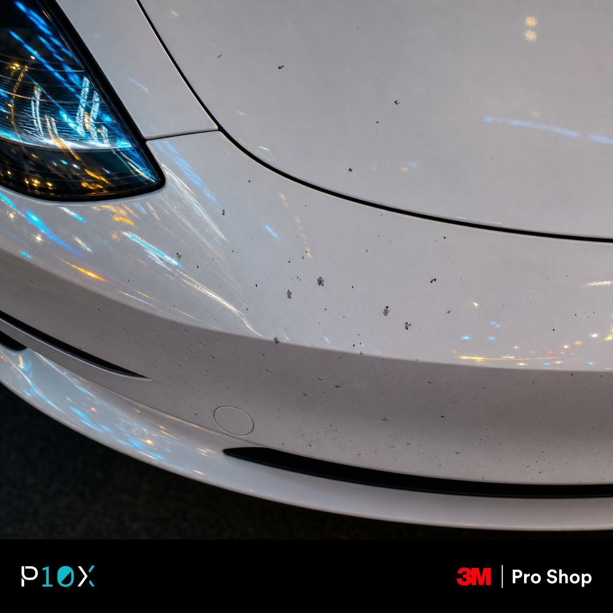 A macro close-up shot of a white Tesla Model 3's front bumper showing small stone chips and paint damage in a Kuala Lumpur urban setting.