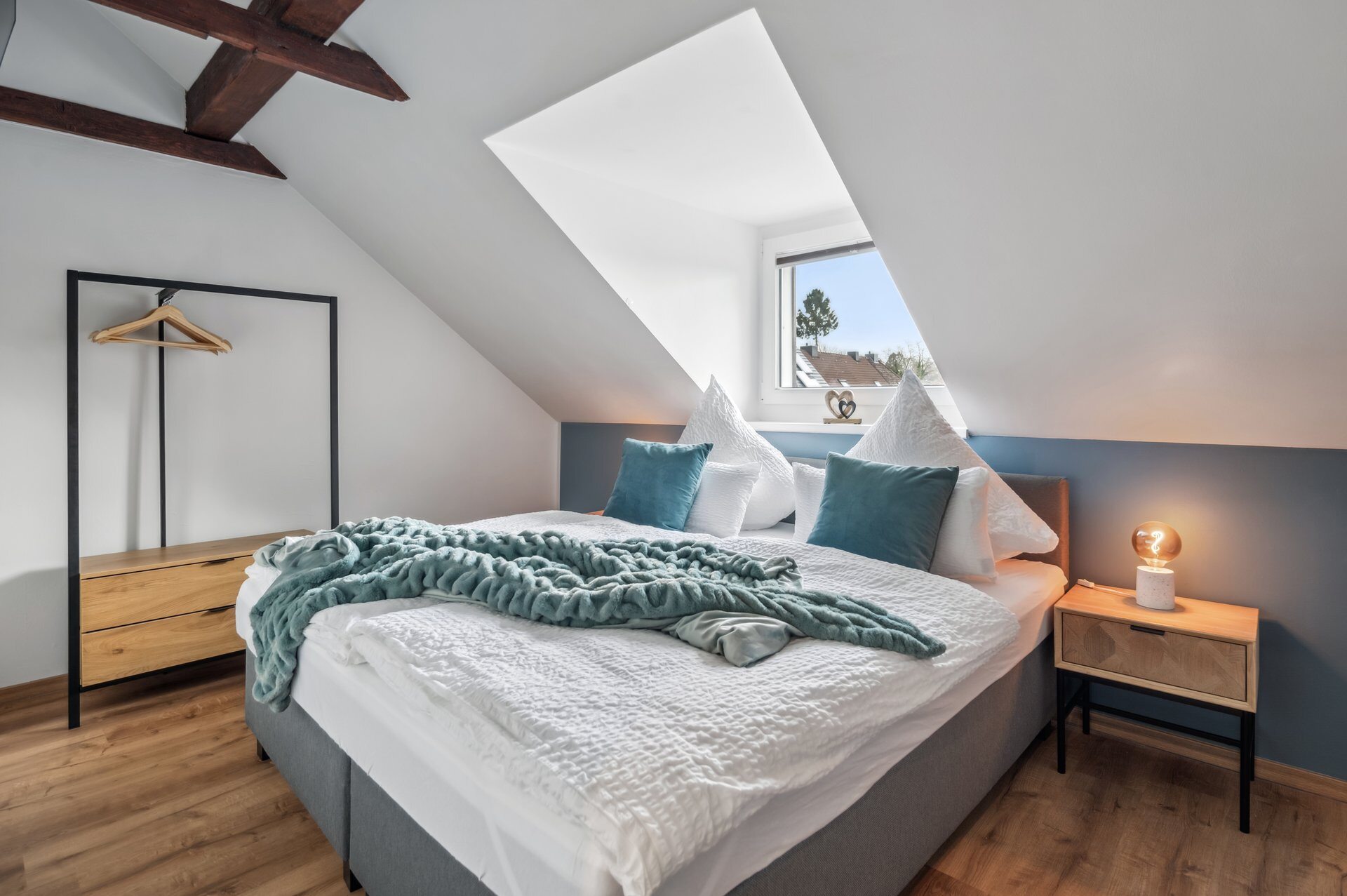 Schlafzimmer unter der Dachschräge mit Kingsize-Bett und Nachttisch
