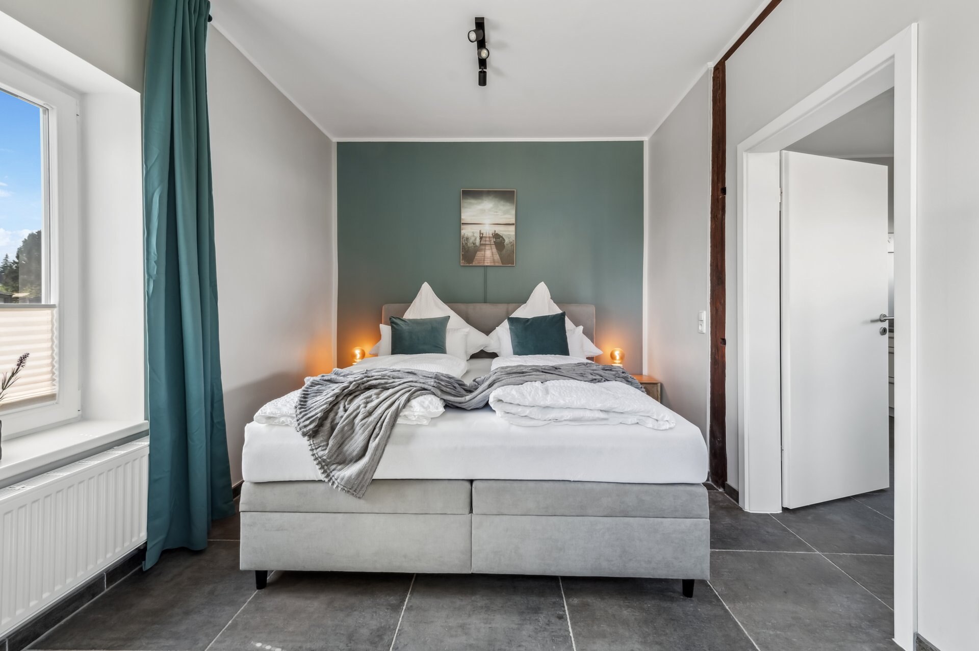 Schlafzimmer im Erdgeschoss mit Kingsize-Boxspringbett und Fenster