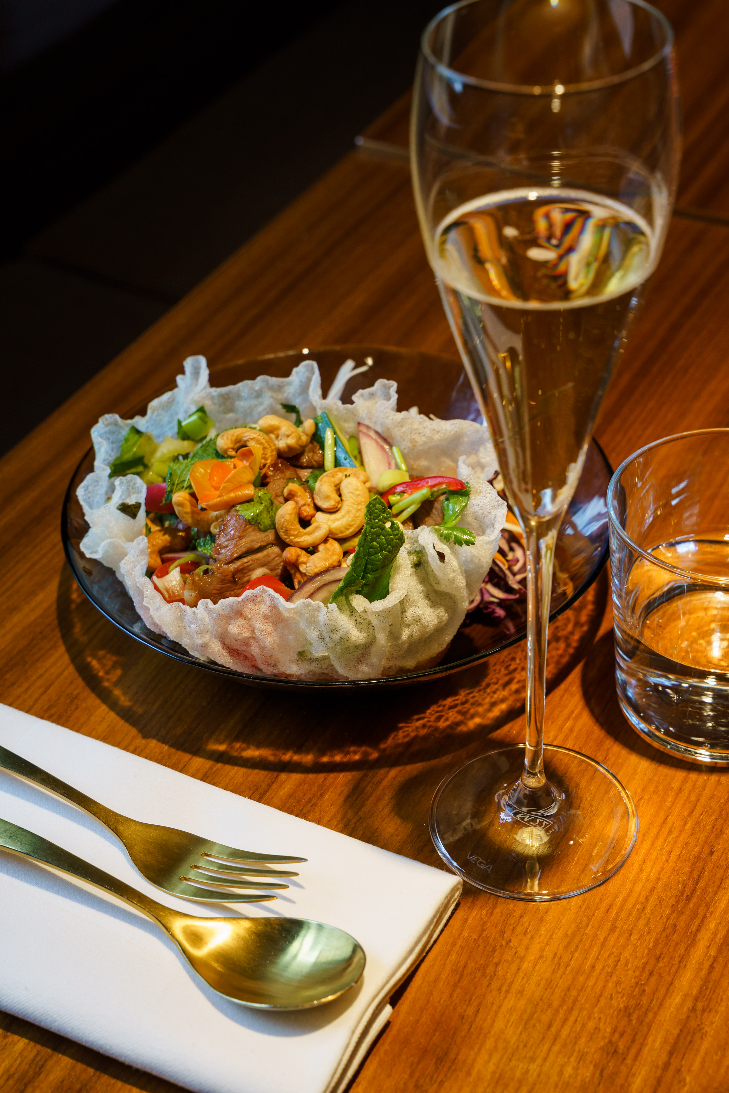 A celebration glass of sparkling wine beside a Thai salad at Umbra