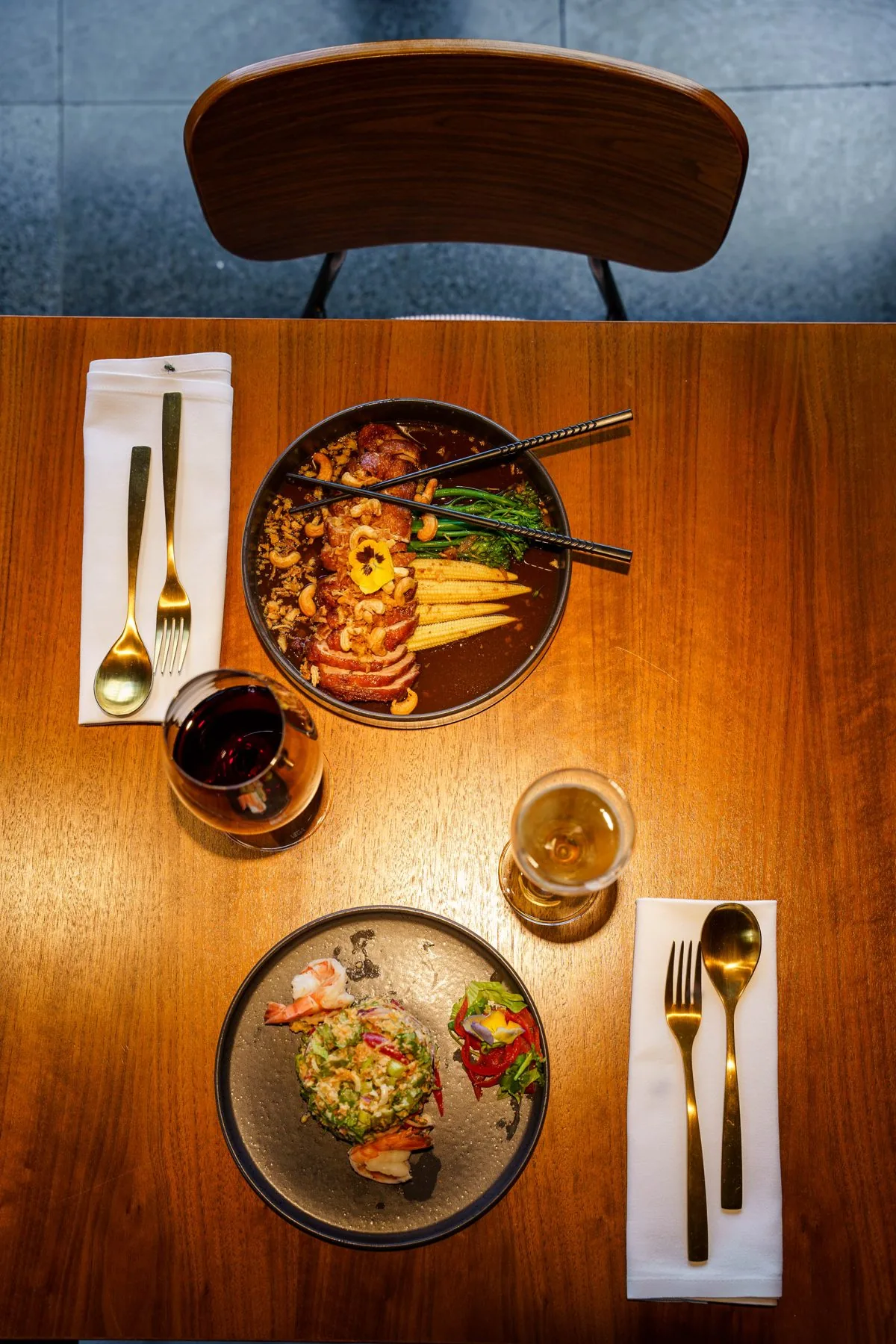 Thai dishes and wine on a table at Umbra, seen from above