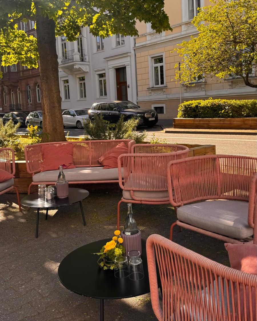 Garden terrace at Umbra with coral rope chairs under the trees on Myliusstraße