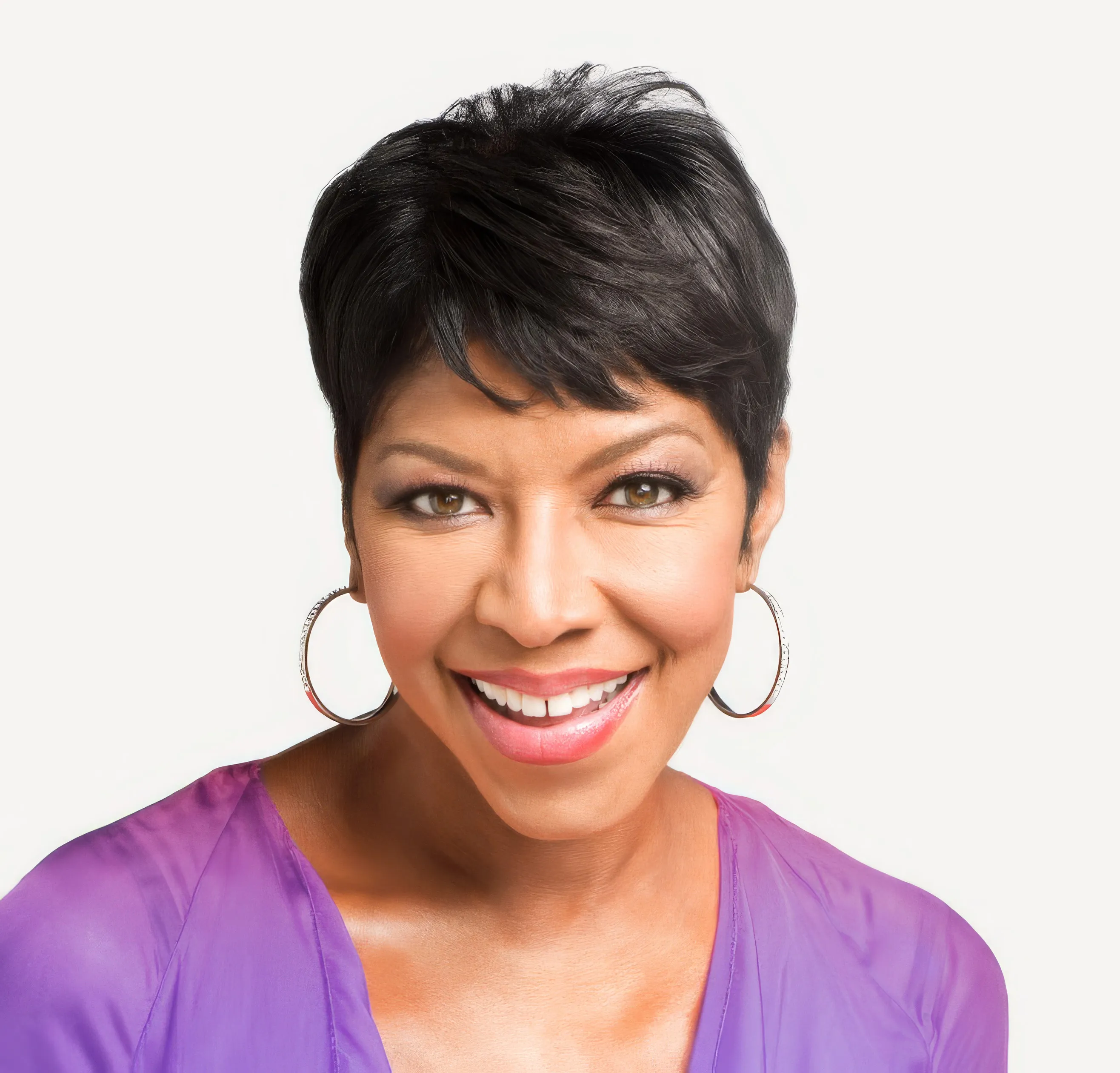 Natalie Cole with big smile and purple blouse.