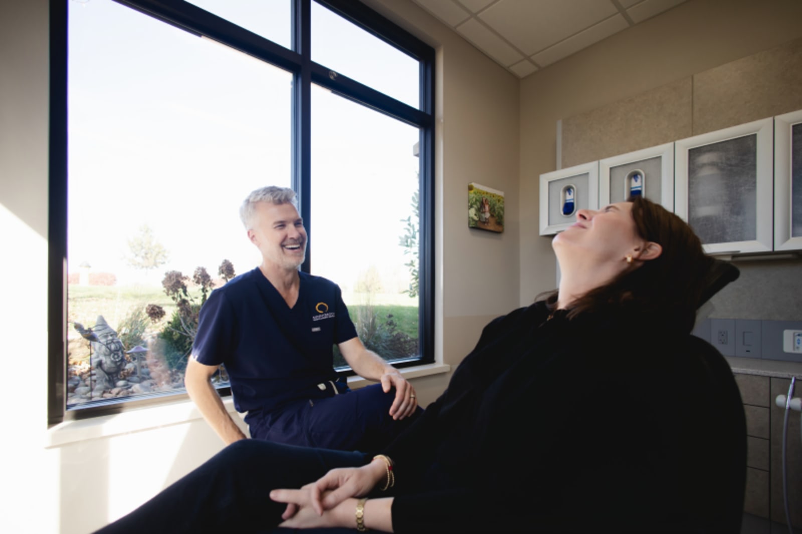 Dentist consulting with patient by window during appointment