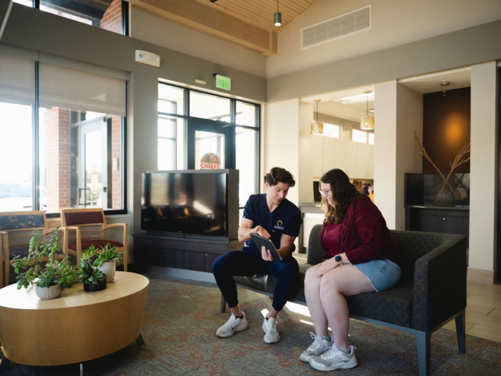Patients sitting in a modern dental office waiting room with contemporary furniture and natural lighting.