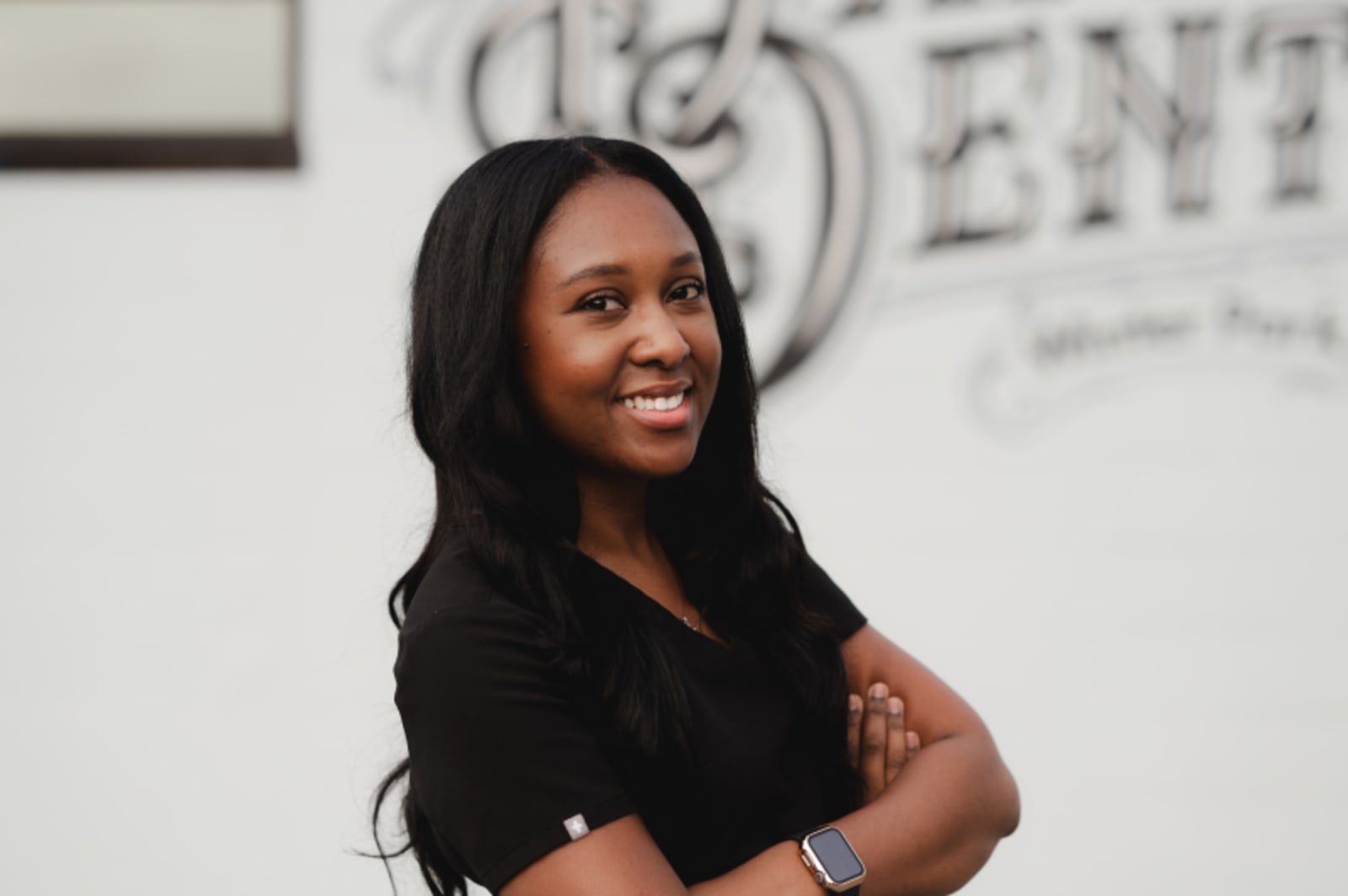 Confident female dental professional in black scrubs smiling at camera in office