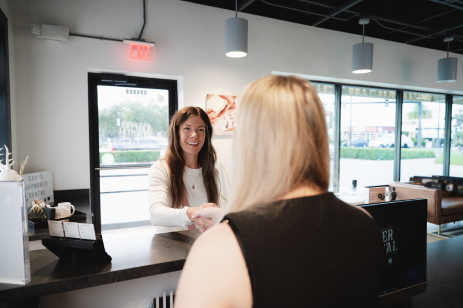 Patient consultation at reception desk with dental professional in welcoming office environment