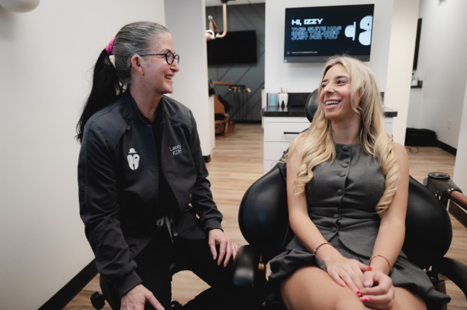 Two women smiling during a consultation in a dental office treatment room.