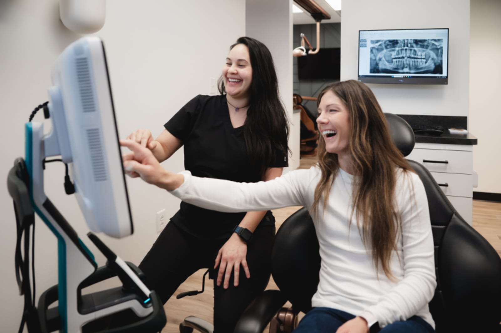 Two dental professionals reviewing a smile makeover treatment plan on a computer screen in an office consultation.