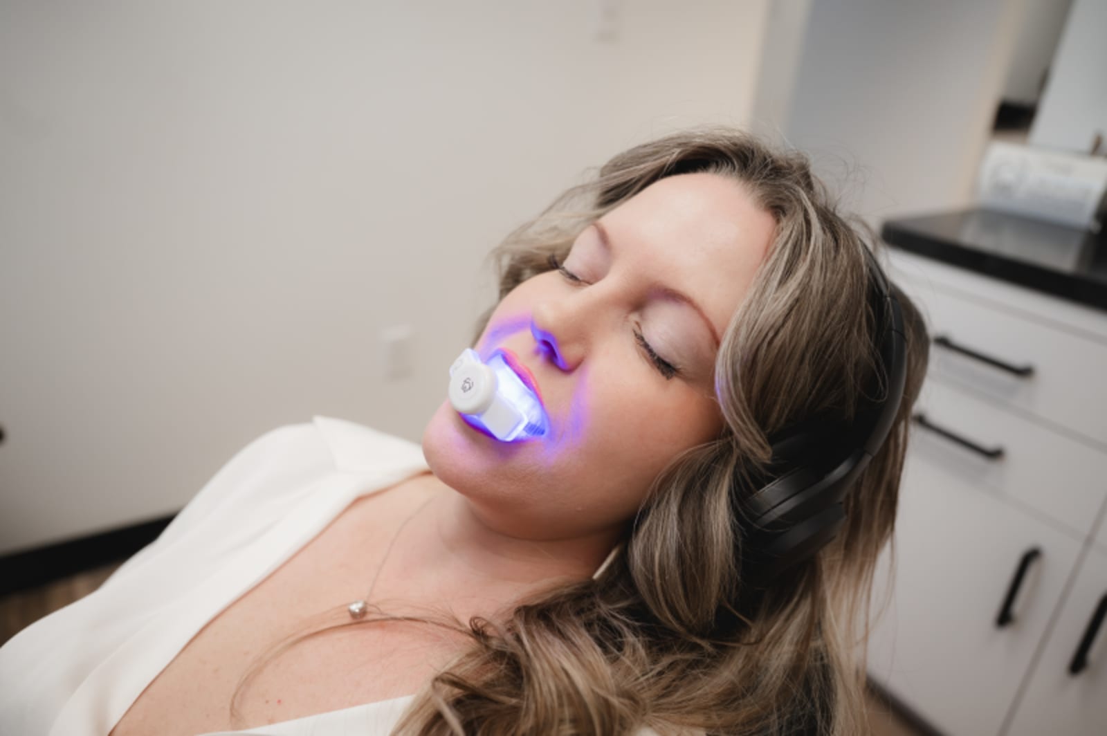 Patient receiving teeth whitening treatment with LED light in dental chair