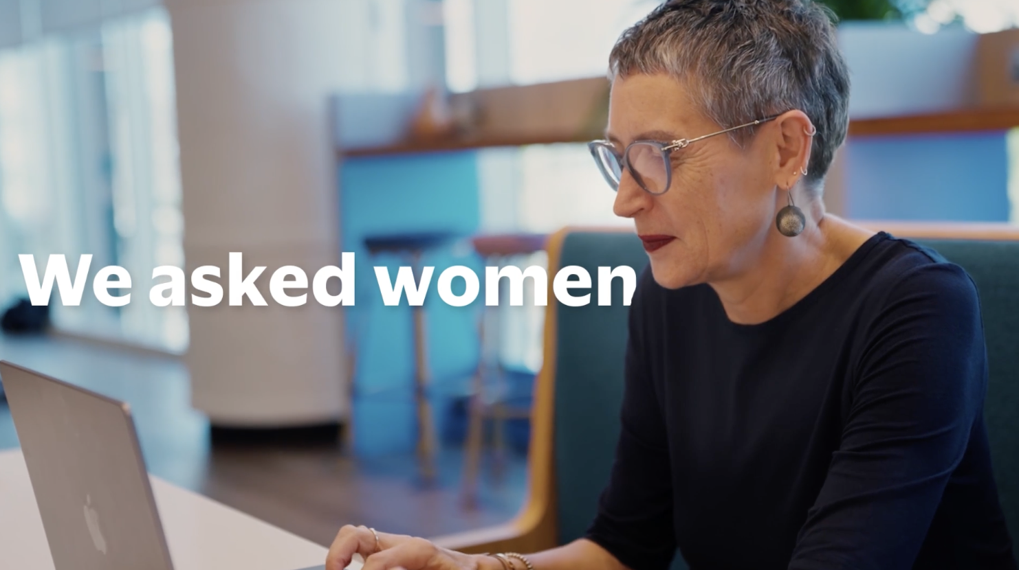 "We asked women" title card over a video still of a woman with short grey hair and glasses seated at a laptop in an office lounge setting.