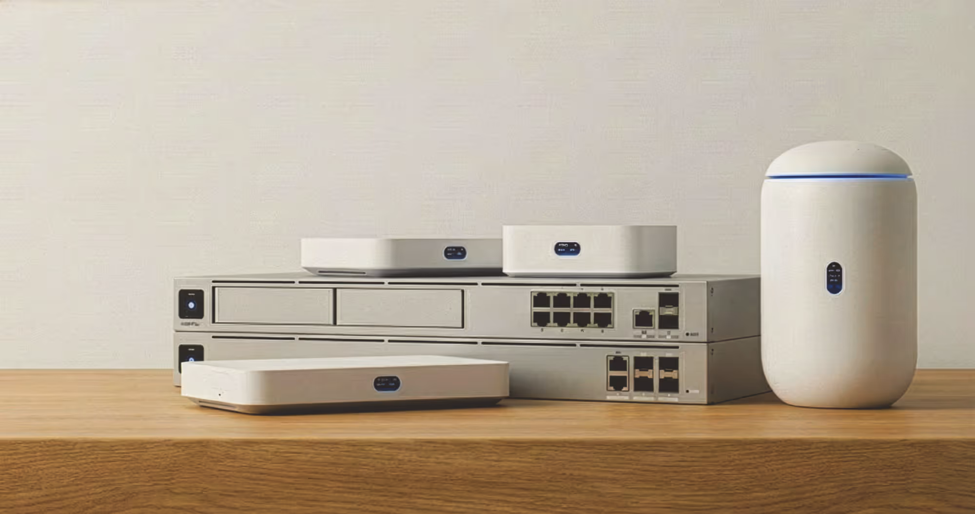 Modern network devices including routers and switches arranged on a wooden surface against a plain background.