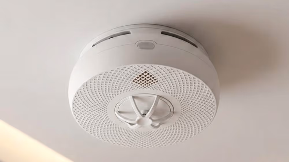 White smoke detector mounted on a ceiling.
