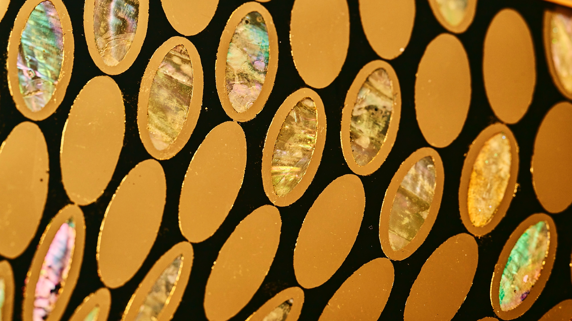 Close-up of mother-of-pearl inlay and gold leaf ovals on SOLEIL's reverse-gilded verre eglomise glass