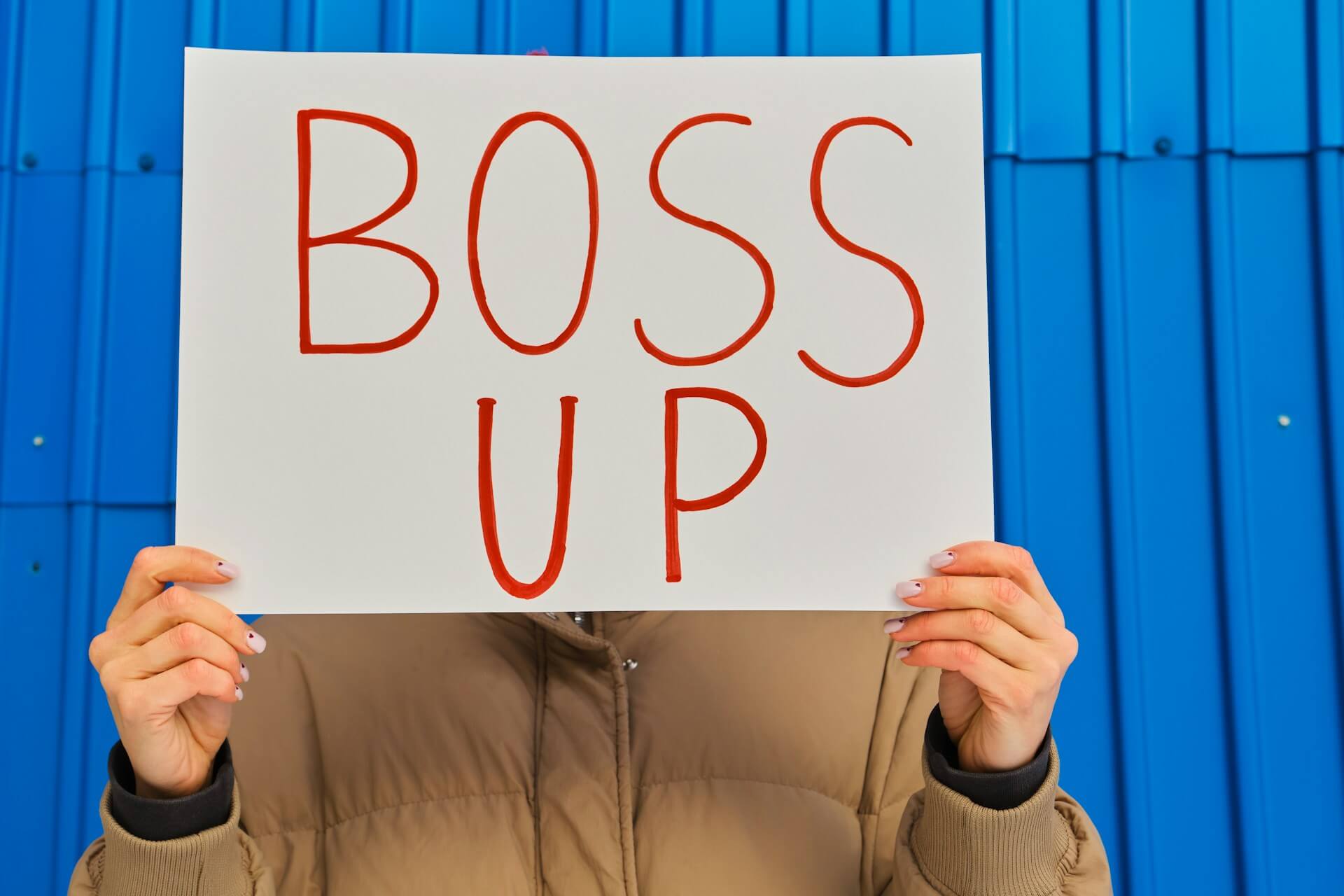 Person holding a Boss Up sign — why burnout prevention starts with leadership, not employee resilience programs