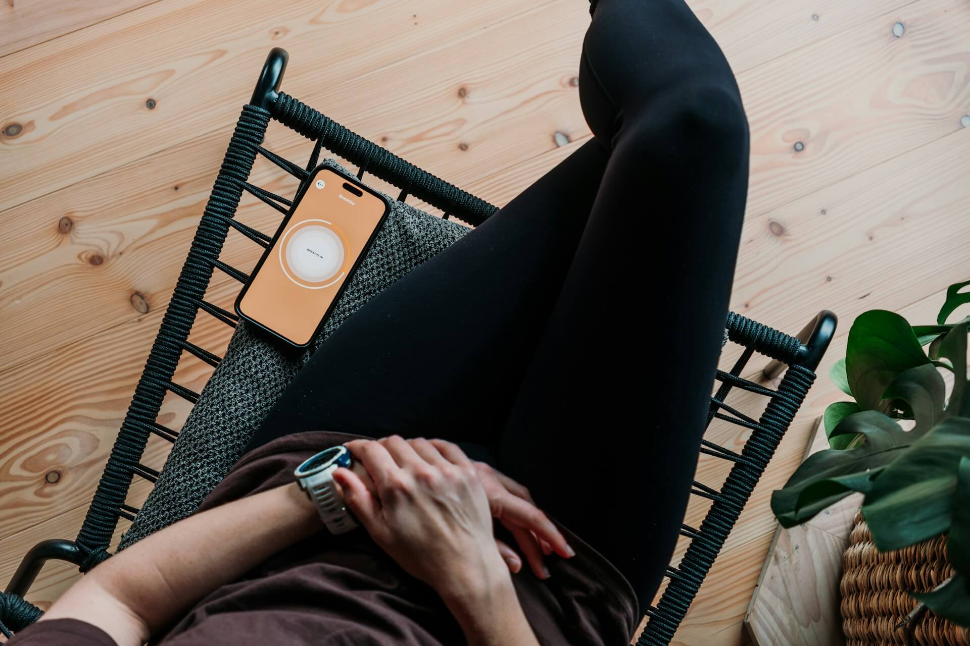 Person sitting with a wellness app open on their phone. The kind of workplace wellbeing program that sounds good on paper but rarely gets used