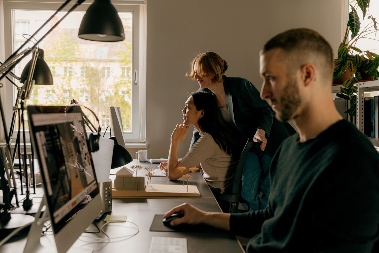 Three colleagues collaborating at a desk in a positive and engaged workplace environment