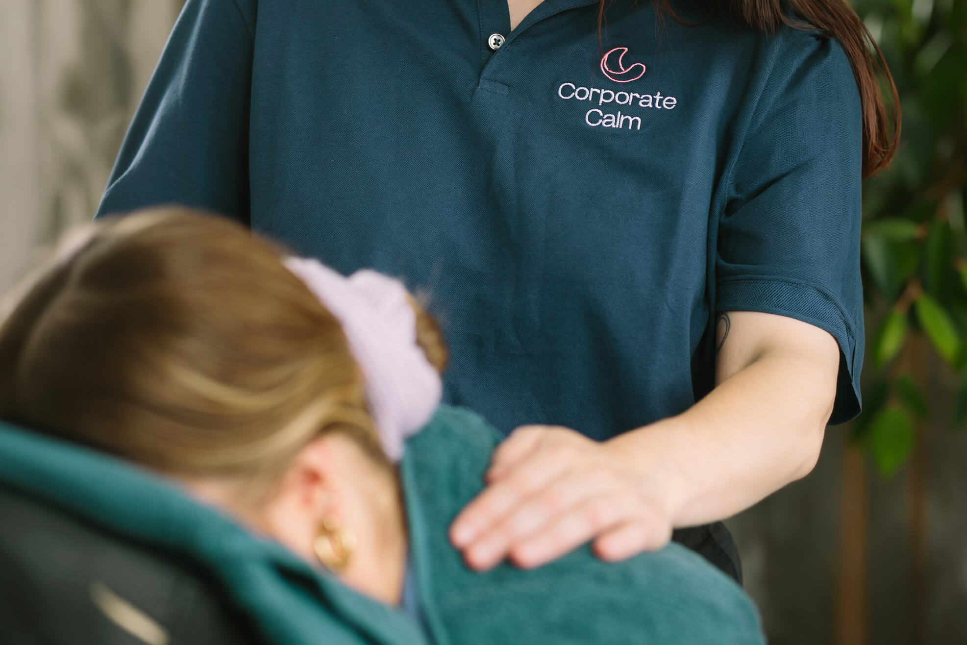 Corporate Calm branded therapist working on a client's shoulders during a workplace massage
