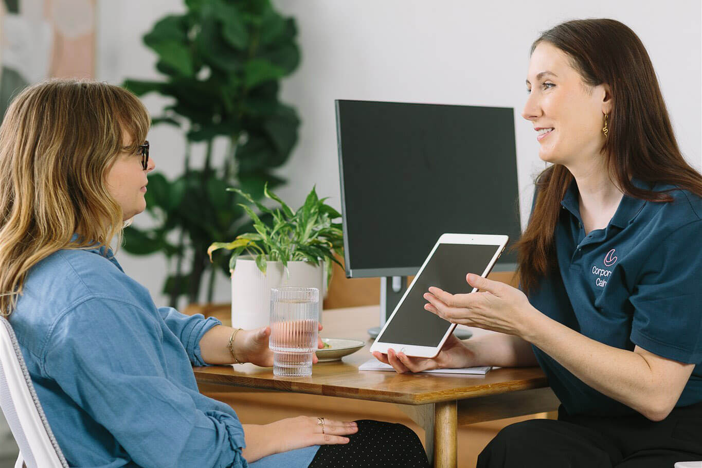 Corporate Calm team member discussing a workplace massage program with a client on a tablet