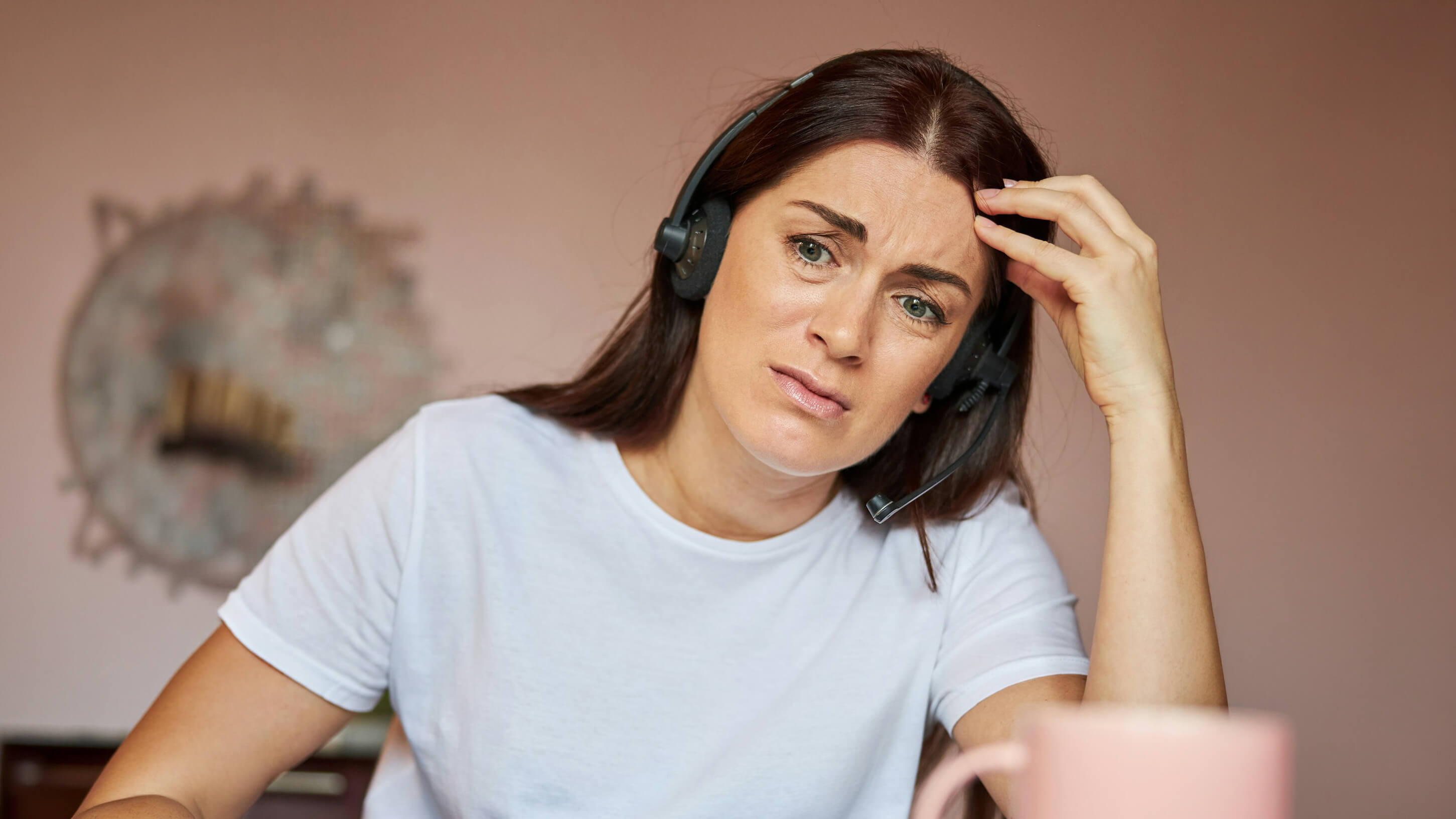Employment services consultant wearing a headset looking emotionally fatigued at her desk